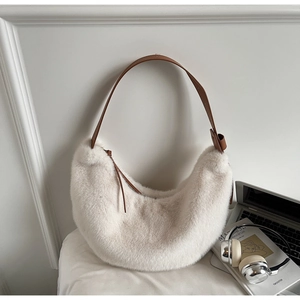 Detail of a creamy white faux fur hobo bag with slim brown leather strap and soft texture