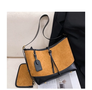 Detail of vintage tote set in brown suede and black leather with metal bottom studs