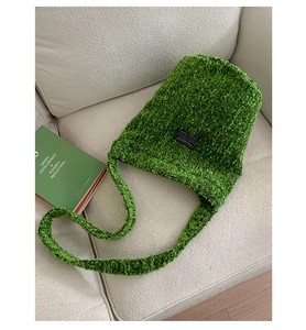 Detailaufnahme der grasgrünen Fleece-Beuteltasche mit Fashion-Label auf Stoffsofa