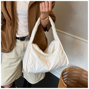Detailed view of white quilted shoulder bag featuring soft textured diamond stitching