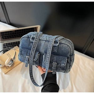 Detailed view of blue denim shoulder bag with metal buckles and front pockets