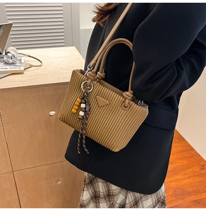 Sac fourre-tout en velours côtelé marron plissé avec charms porté par un mannequin