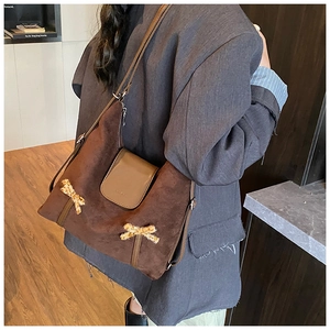 Sac à épaule en daim marron avec nœuds léopard porté sur le côté du mannequin