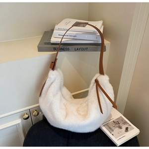 Detail of soft white plush fabric and brown leather strap on hobo shoulder bag