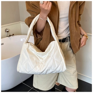 Close-up of white quilted puffer shoulder bag showing soft padded texture and wide strap