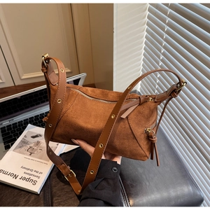Close-up of caramel suede dumpling bag with decorative gold eyelets and textured finish