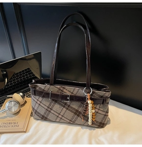 Close-up of retro plaid tote bag with leather strap and decorative wood bead charm