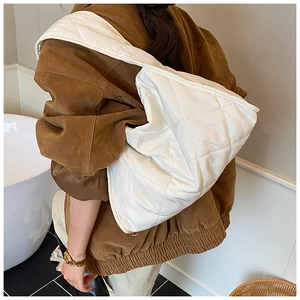Detail of white quilted hobo bag worn by model in a stylish indoor lifestyle setting