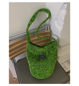 Nahaufnahme der grasgrünen Plüsch-Beuteltasche mit Fashion Instinct Webetikett und Textur