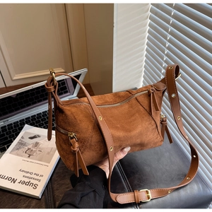 Detail of vintage brown suede shoulder bag with dual zippers and tassel accents