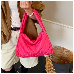 Detail view of hot pink puffer handbag showing the large quilted stitch pattern and nylon texture