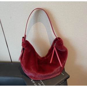 Detail of burgundy plush faux fur shoulder bag with smooth leather strap and tassels