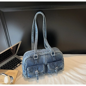 Detailed close-up of dark blue washed denim shoulder bag with silver buckles and dual pockets