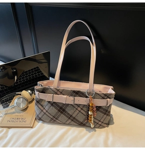 Detail of checkered plaid shoulder bag with wooden bead tassel in a workspace setting