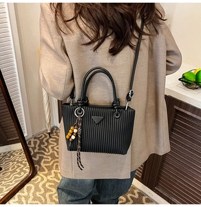Modèle portant un sac seau plissé noir avec pampille en perles et logo triangle