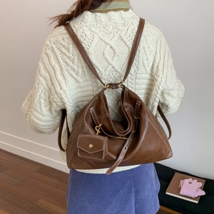 Détail du sac à dos en cuir marron rétro avec pochette porté sur pull beige