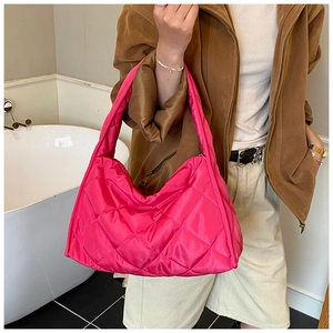 Close-up of vibrant rose red quilted shoulder bag with soft padding and rhombus texture