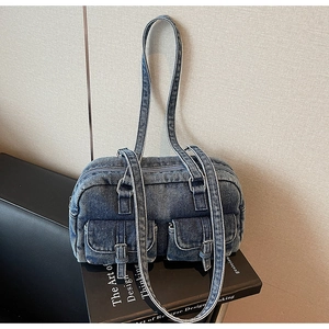 Detail of vintage blue denim pillow bag featuring double front buckle pockets and silver hardware