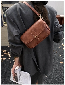 Brown vintage leather shoulder bag styled with a grey blazer for a modern office look