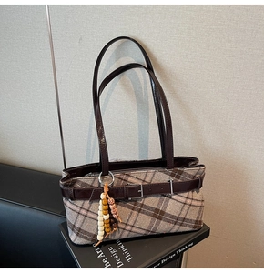 Detail showing brown plaid tweed texture and bohemian bead charm on retro shoulder bag
