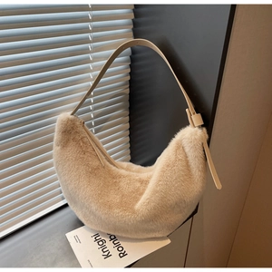 Detail view of cream faux fur hobo bag with adjustable leather strap near a window
