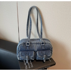 Detail of vintage blue denim shoulder bag featuring dual front pockets and silver buckles