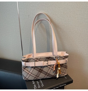 Close-up of retro plaid underarm bag with pink leather strap and decorative beads