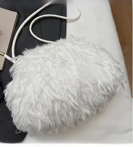 Gros plan sur un sac bandoulière en fausse fourrure blanche avec plumes douces et sangle