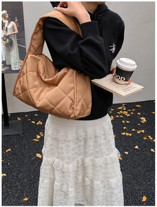 Detailed view of a brown quilted tote bag with diamond stitching shown in a street style look