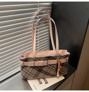 Detail of checkered plaid underarm bag with pink leather straps and tassel charm detail