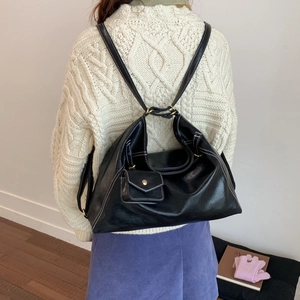 Détail d'un sac à dos noir en similicuir avec surpiqûres blanches et mini pochette