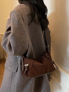 Retro brown suede dumpling shoulder bag worn with a stylish tweed coat in a warm indoor setting