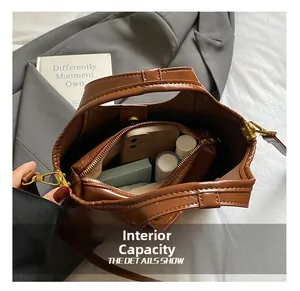 Vue intérieure d'un sac seau spacieux en daim marron avec compartiments et objets du quotidien