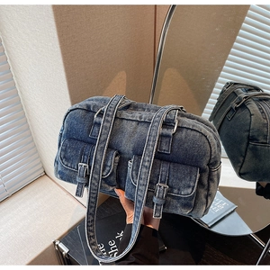 Close-up of vintage blue denim pillow bag featuring dual front pockets and metal buckles