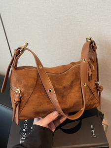 Vintage brown suede dumpling bag with gold eyelets and tassel, autumn 2026 style