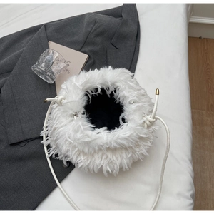 Gros plan sur le sac seau blanc en plumes avec détails métalliques dorés et cordon