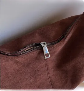 Close-up of smooth silver zipper on a dark brown suede tote bag with matte texture