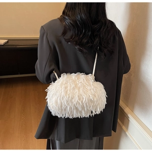 Détail d'un sac nuage blanc en fausse fourrure porté sur un blazer noir élégant et chic