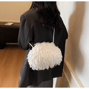 Gros plan sur un sac à bandoulière en fausse fourrure blanche porté sur un blazer noir