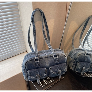 Detail shot of blue denim shoulder bag with dual front pockets and strap accents