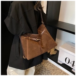 Brown suede tote bag shown on shoulder with gold hardware and spacious interior detail