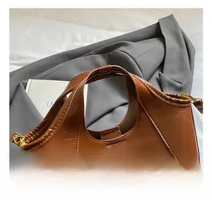 Détail du sac seau marron en daim avec poignée intégrée et fermeture à glissière dorée élégante