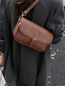 Retro brown PU leather crossbody bag worn by a model in a charcoal blazer suit