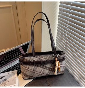 Detail of vintage plaid shoulder bag with brown leather strap and wood bead ornament