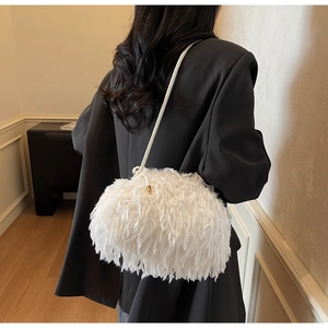 Détail du sac bandoulière blanc en plumes avec attaches dorées sur un blazer noir