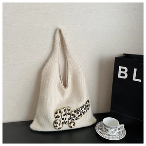 Close-up of cream knit tote bag featuring leopard print Mama embroidery and woven texture
