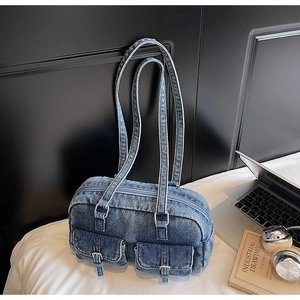 Detailed view of a vintage denim shoulder bag with two front pockets on a lifestyle desk