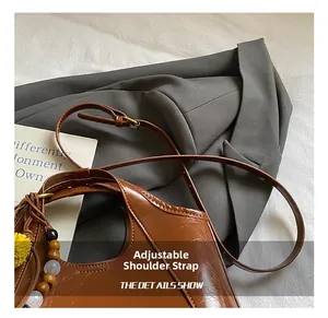 Détail d'un sac bandoulière en cuir ciré marron avec bandoulière réglable et breloque