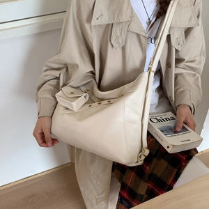 Détail du sac hobo crème avec bandoulière réglable et pochette sur manteau beige
