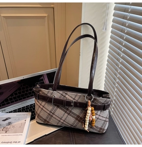 Detailed view of vintage plaid underarm bag with leather trim and wooden bead charm